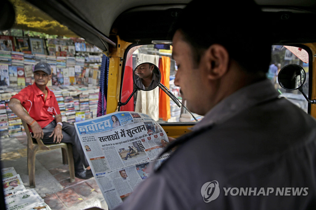 지난 6일 인도 수도 뉴델리에서 삼륜차(오토릭샤) 운전사가 영화배우 살만 칸의 구속 사실이 1면에 실린 신문을 읽고 있다.[AP=연합뉴스 자료사진]