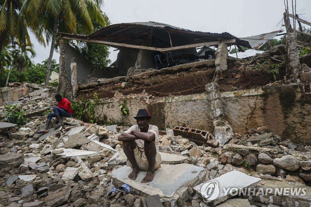 17일(현지시간) 지진으로 무너진 건물 앞에 앉아있는 아이티 플뢰랑 주민