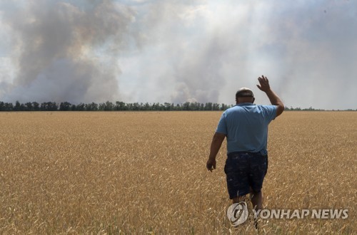 지난달 초 우크라이나 드니프로 논밭에서 교전으로 인한 화재 현장 뒤로 보이는 농부의 모습