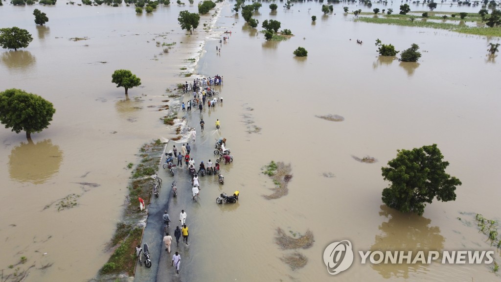 지난 19일 나이지리아 홍수로 사람들이 물을 헤치며 걷는 모습