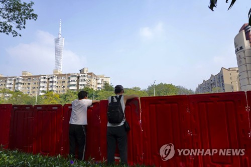 (AP=연합뉴스) 지난 11일 중국 광둥성 광저우 주민들이 바리케이트 너머로 봉쇄된 하이주구를 바라보는 모습. 2022.11.13. 