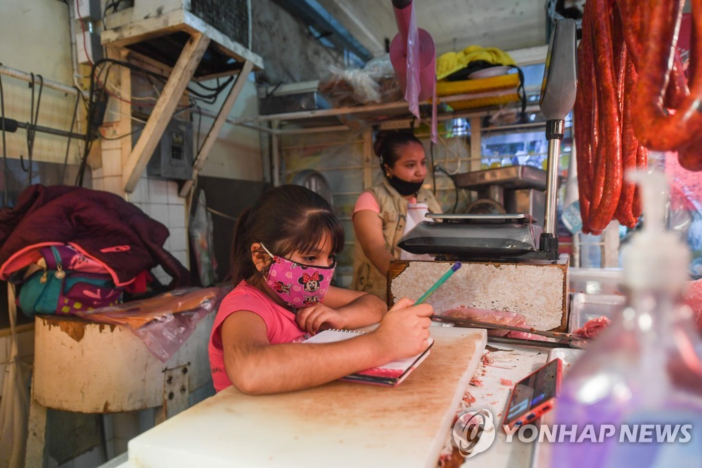 엄마가 일하는 정육점에서 스마트폰으로 수업을 듣는 멕시코 어린이