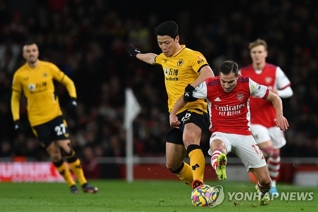 In this AFP photo, Hwang Hee-chan of Wolverhampton Wanderers (L) battles Cedric Soares of Arsenal for the ball during a Premier League match at Emirates Stadium in London on Feb. 24, 2022. (Yonhap)