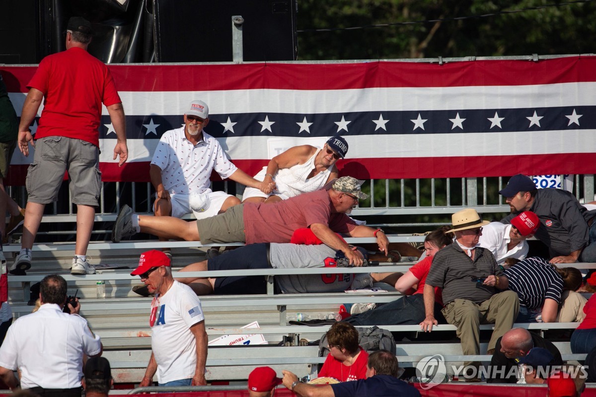 Trump supporters are seen lying in the stands after hearing gunshots fired at Republican candidate Donald Trump at a campaign event at the Butler Farm Show Inc. in Butler, Pennsylvania, on July 13, 2024, in this photo released by AFP. (Yonhap)