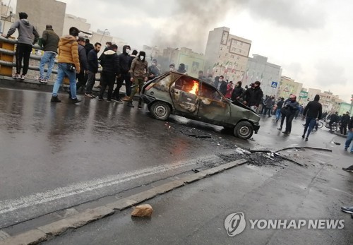 휘발유 가격 인상에 항의하는 이란 시위대가 차량에 불을 붙이고 이를 지켜보고 있다.