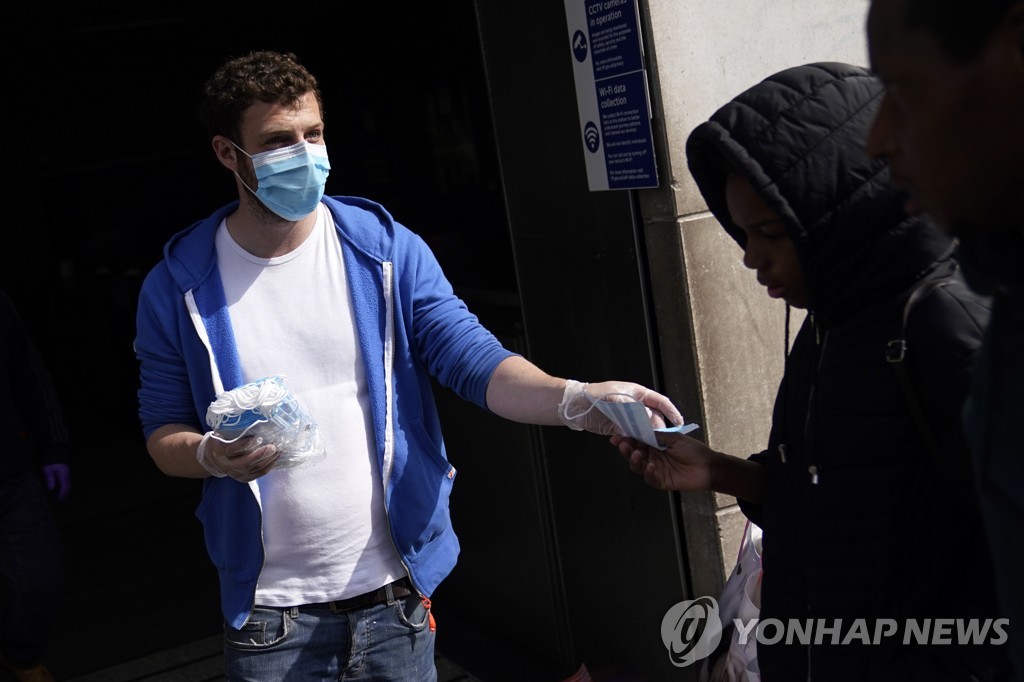 지난 11일 영국 런던에서 한 시민단체 활동가가 행인에게 마스크를 무료로 나눠주는 모습 [EPA=연합뉴스 자료사진]