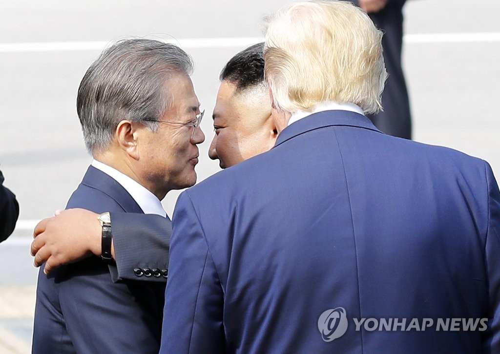 U.S. President Donald Trump (R) watches the leaders of the two Koreas -- Moon Jae-in (L) and Kim Jong-un -- hugging each other in Panmunjom on June 30, 2019. (Yonhap)