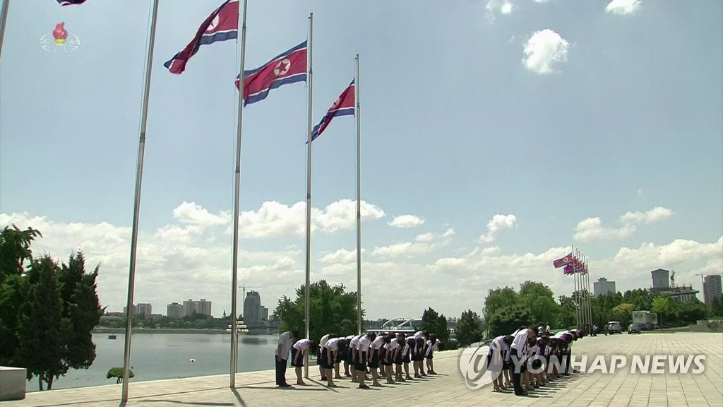 This photo, captured from North Korea's Central TV, shows North Korean civilians paying silent tribute to the country's late founder, Kim Il-sung, at noon on July 8, 2019, the 25th anniversary of his death, as the North Korean flag flies at half-mast. (For Use Only in the Republic of Korea. No Redistribution) (Yonhap)