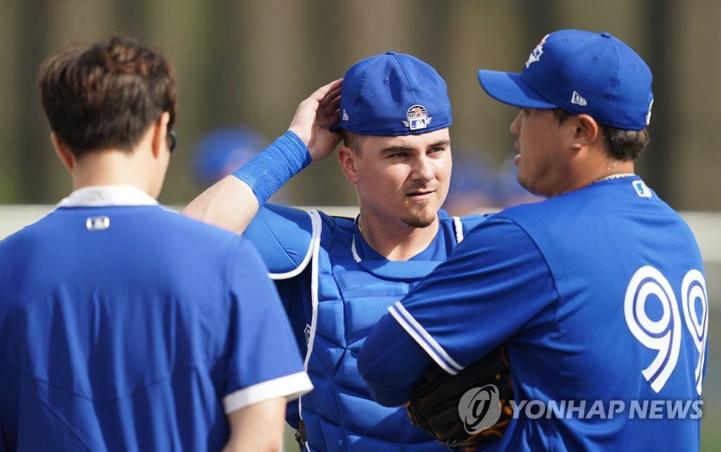 Toronto Blue Jays' catcher Reese McGuire (C) speaks with pitcher Ryu Hyun-jin (R), with the help of Ryu's interpreter, Bryan Lee, before Ryu's bullpen session at the Player Development Complex, outside TD Ballpark, in Dunedin, Florida, on Feb. 13, 2020. (Yonhap)