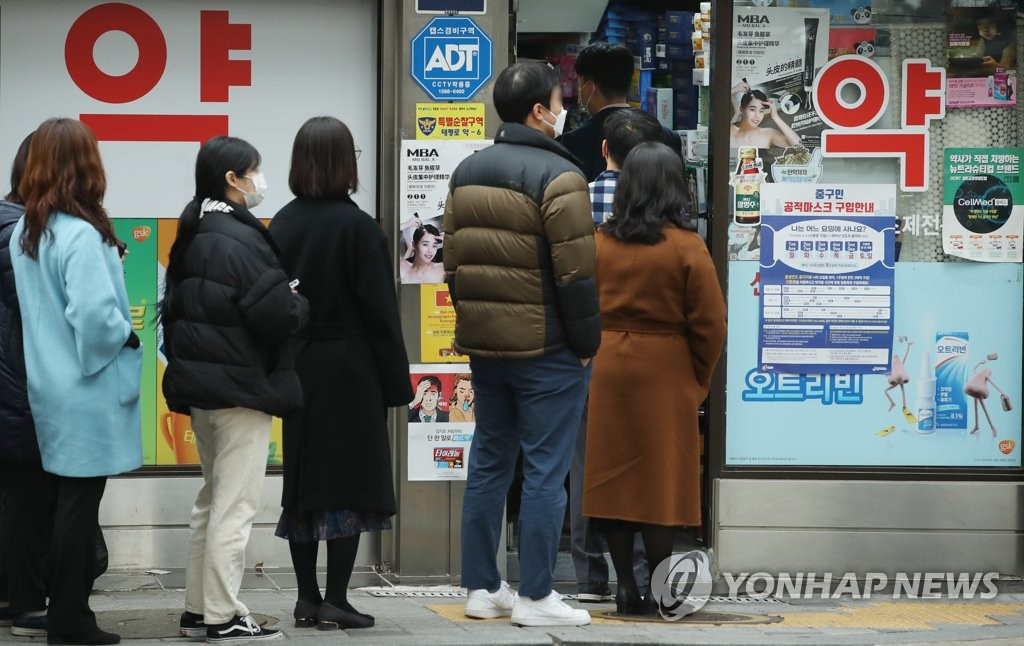 This photo, taken on March 17, 2020, shows people standing in a queue to buy face masks at a pharmacy in central Seoul. (Yonhap)
