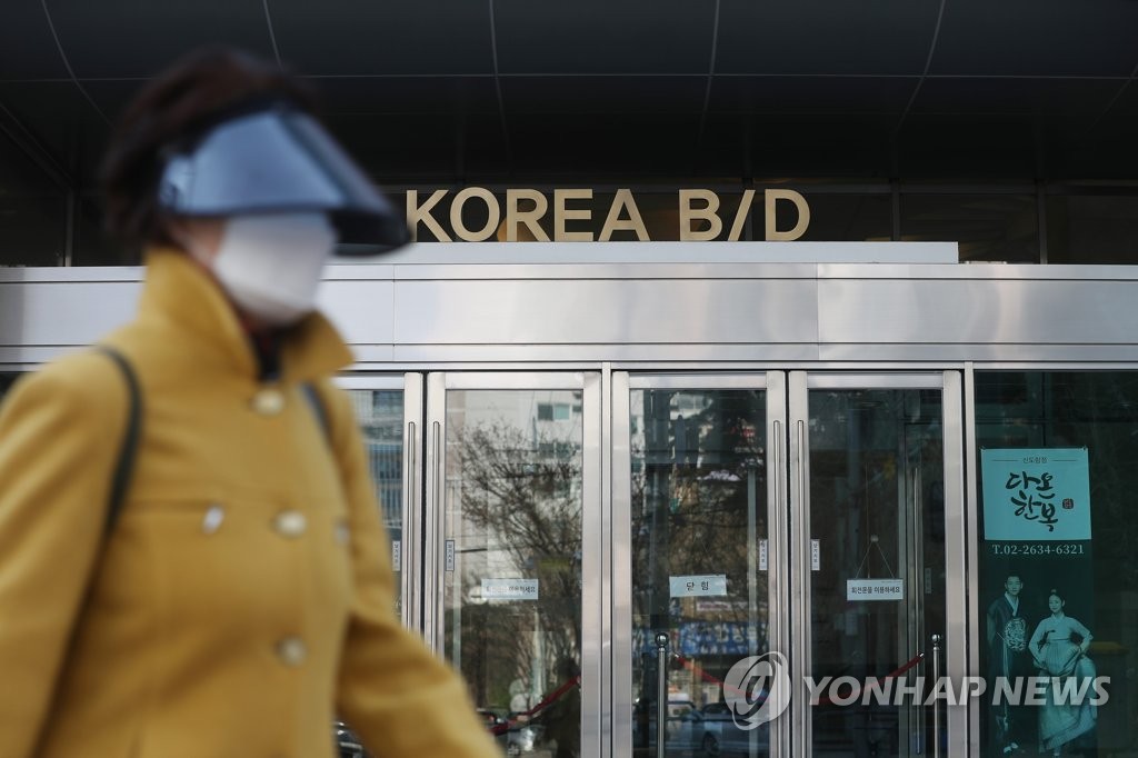 This photo, taken March 23, 2020, shows a woman passing by the Korea Building in the southwestern Seoul ward of Guro. A cluster infection occurred at a call center at the building. (Yonhap)