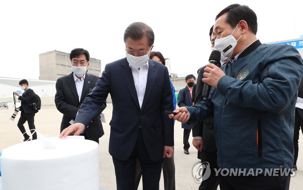 President Moon Jae-in (2nd from R) receives a briefing on an industrial product at the Kolon Industries plant in the national industrial complex in Gumi, North Gyeongsang Province, on April 1, 2020. (Yonhap)
