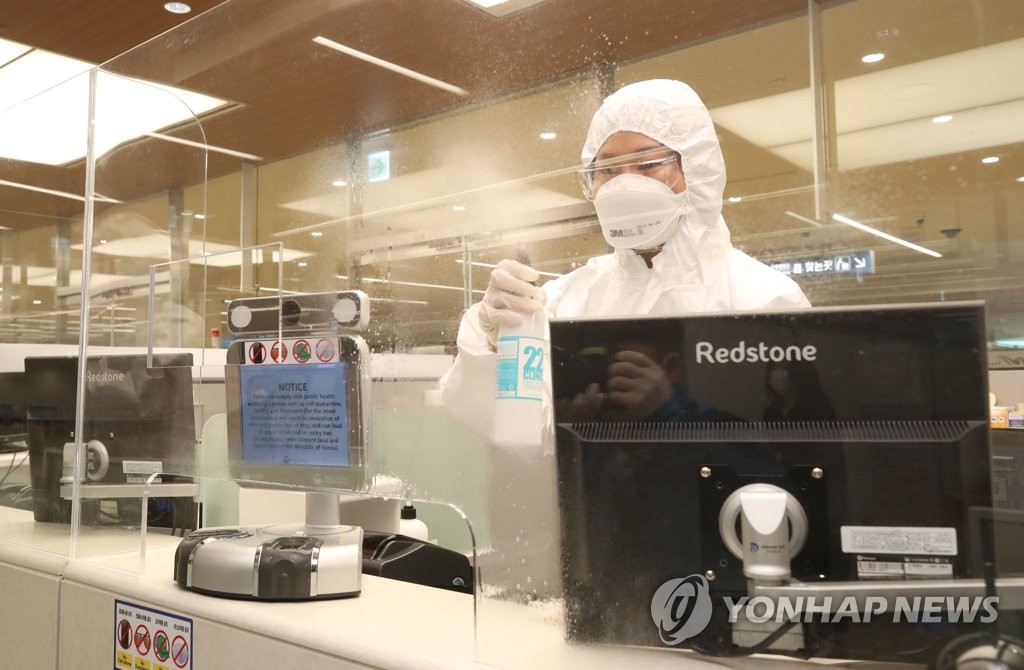 An immigration officer who guides international arrivals showing virus symptoms disinfects her booth at Incheon International Airport, west of Seoul, on April 8, 2020. (Yonhap)