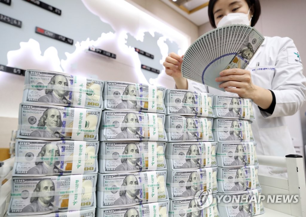 In the undated file photo, a bank official inspects U.S. banknotes at a branch office in Seoul. (Yonhap)