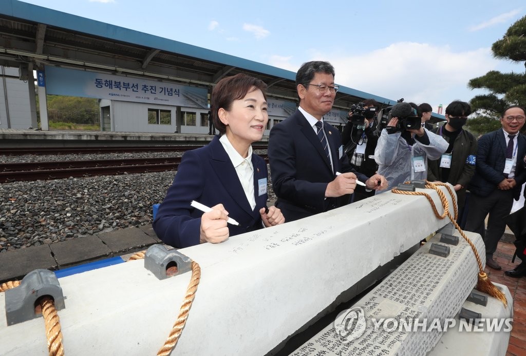 Transportation Minister Kim Hyun-mee (L) and Unification Minister Kim Yeon-chul (2nd from L) sign a railroad tie at a ceremony held at Jejin Station on South Korea's east coast on April 27, 2020, announcing the official start of a project aimed at reconnecting inter-Korean railways. (Pool photo) (Yonhap)