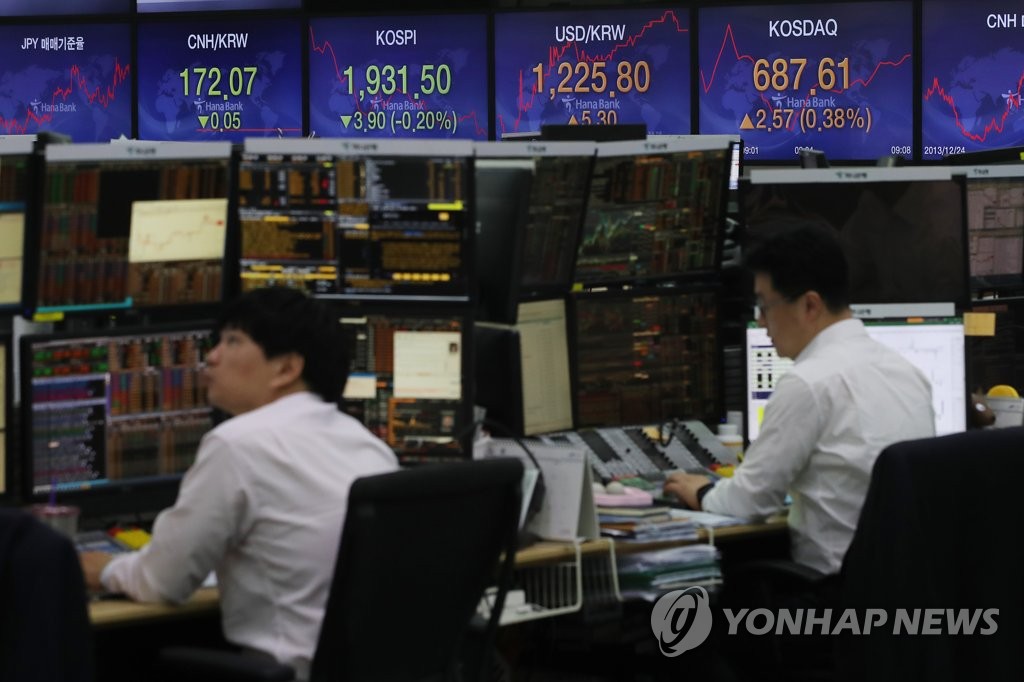 Dealers work in front of an electronic signboard at the headquarters of Hana Bank in Seoul on May 12, 2020. (Yonhap)