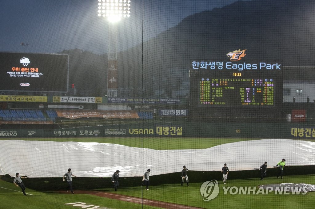 Members of the grounds crew for the Hanwha Eagles cover the field at Hanwha Life Eagles Park in Daejeon, 160 kilometers south of Seoul, with a tarp during a Korea Baseball Organization regular season game between the Eagles and the Doosan Bears on June 13, 2020. (Yonhap)