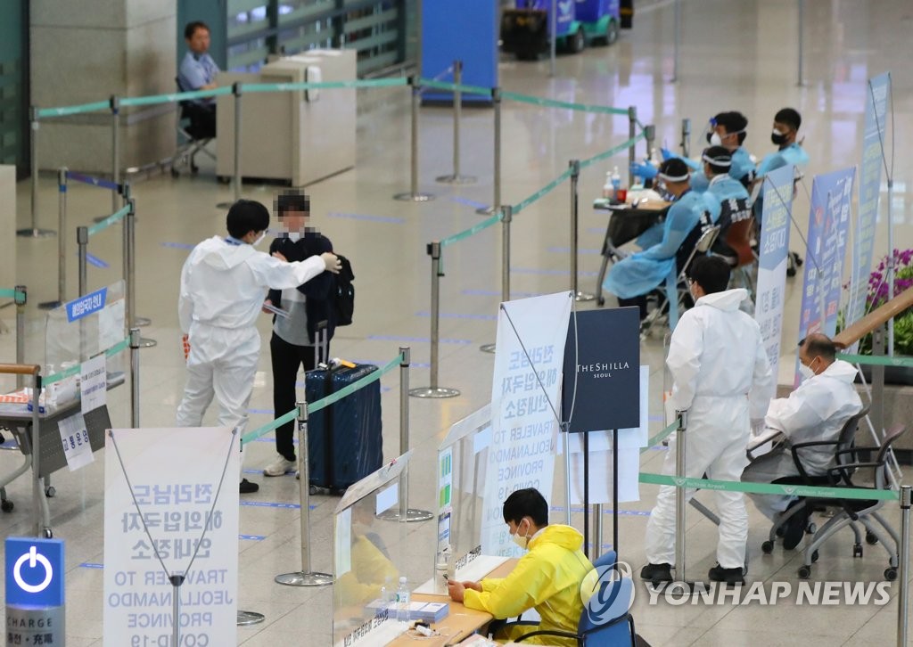A health worker explains quarantine measures to an international arrival at Incheon International Airport, South Korea's main gateway west of Seoul, on June 22, 2020. (Yonhap)