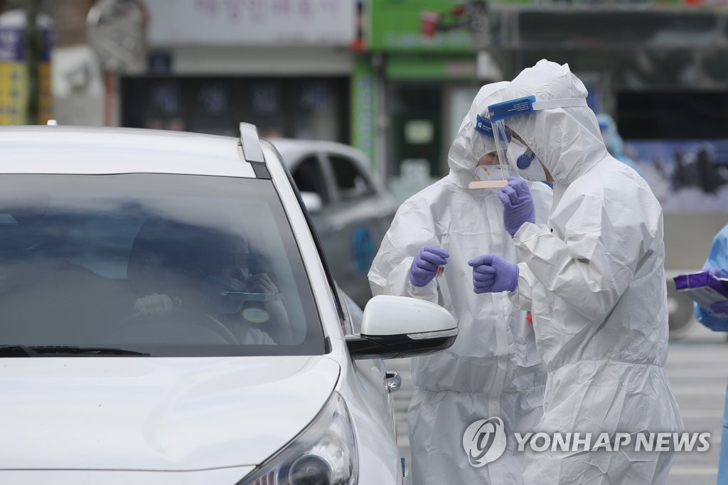 Health workers clad in protective gears conduct virus tests at a drive-thru testing center in Gwangju on July 16, 2020. (Yonhap)