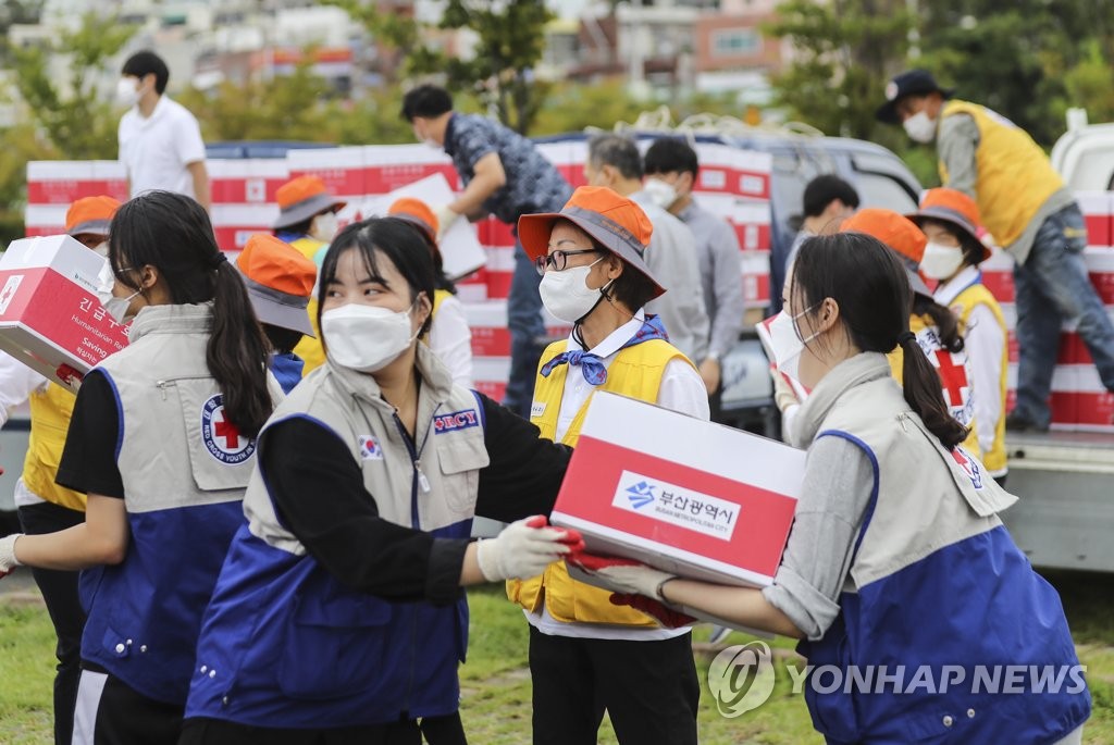 Volunteer workers carry supplies for people under quarantine due to the new coronavirus in the southern port city of Busan on Sept. 23, 2020. (Yonhap)