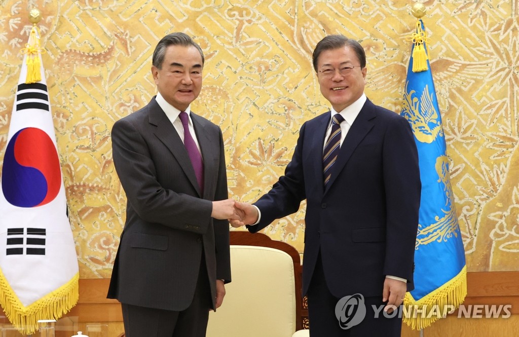 In this file photo from Nov. 26, 2020, South Korean President Moon Jae-in (R) shakes hands with Chinese Foreign Minister Wang Yi at the start of their meeting at Cheong Wa Dae in Seoul. (Yonhap)