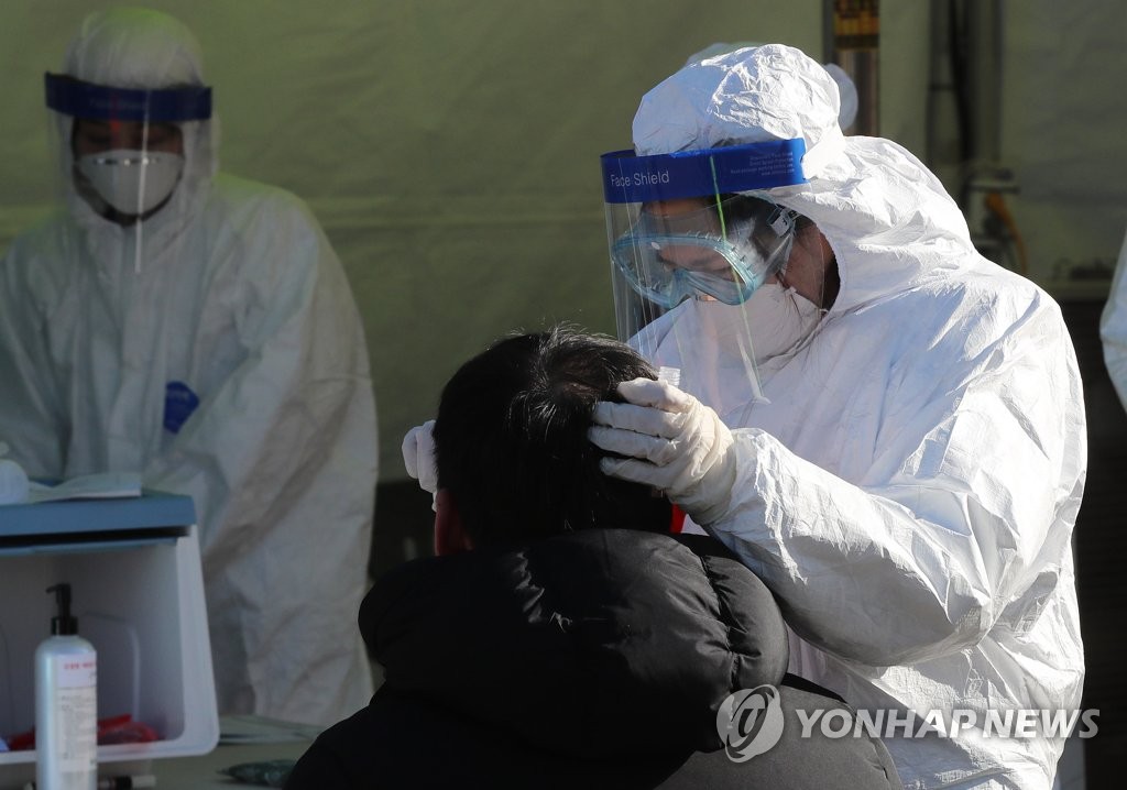 A medical worker carries out COVID-19 tests on visitors at a makeshift clinic in central Seoul on Dec. 15, 2020. (Yonhap)