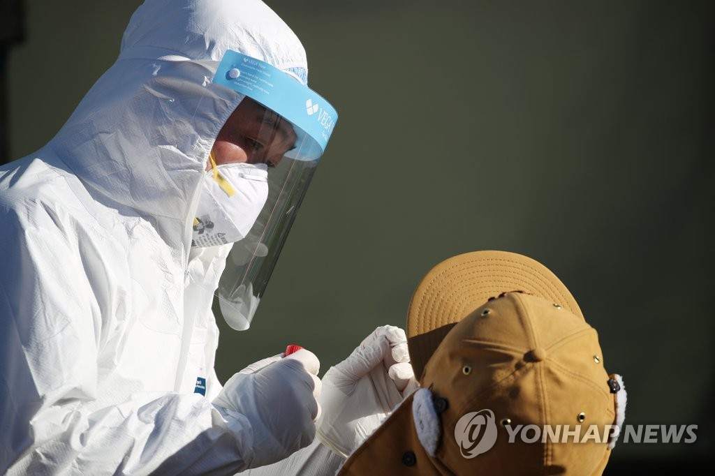 A health worker performs a COVID-19 test on a person in Seoul on Dec. 20, 2020. (Yonhap)