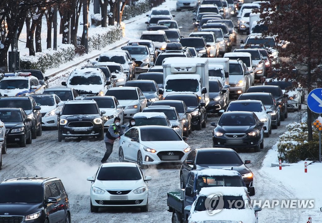 Cars move slowly on a snow-covered road in Suwon, just south of Seoul, on Jan. 7, 2021. (Yonhap)