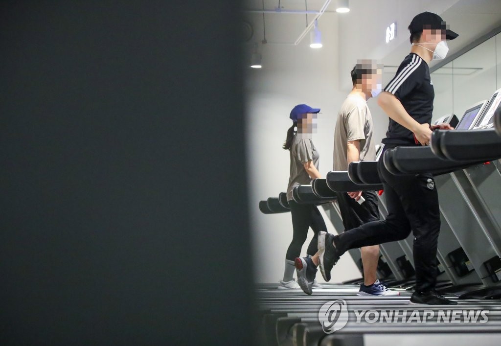 This undated file photo shows people walking and running on treadmills at a gym. (Yonhap)