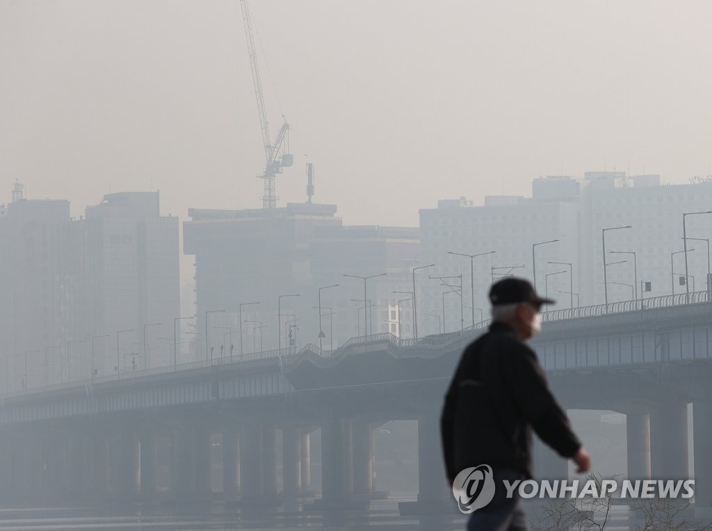 A citizen walks at a riverside park in Seoul on March 11, 2021, as the capital city is shrouded in fine dust air pollution. (Yonhap)
