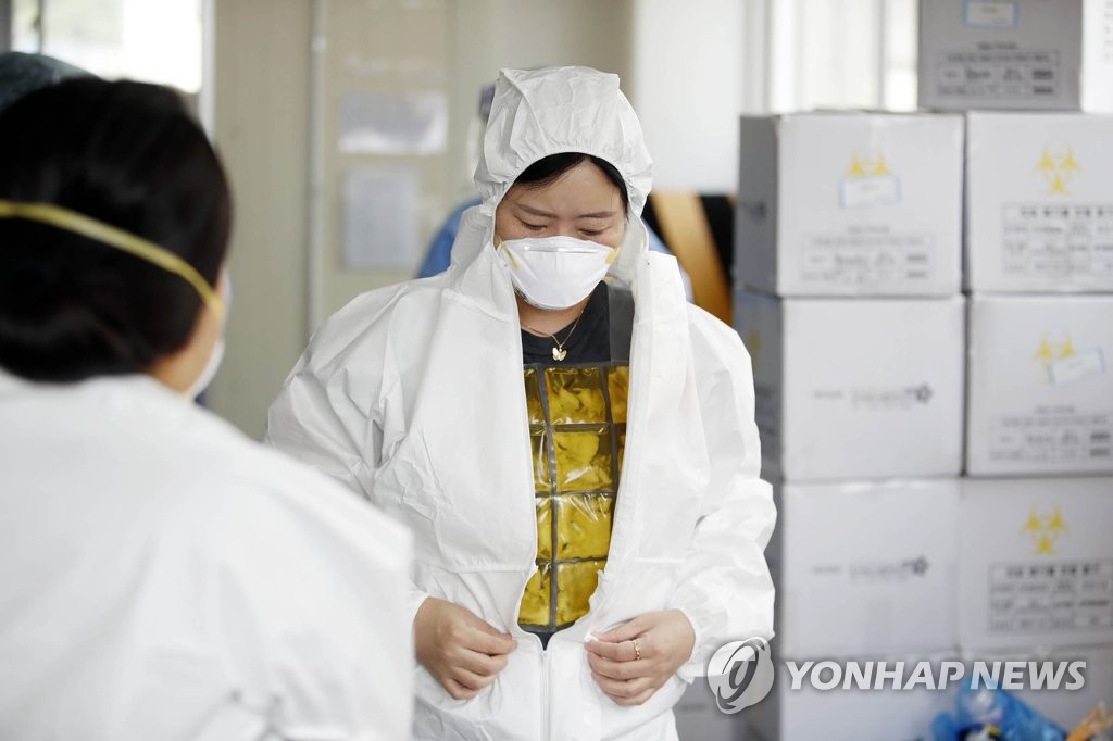 Une membre du personnel médical porte une combinaison de protection ainsi qu'un gilet réfrigérant pour combattre la chaleur dans un centre de dépistage pour le nouveau coronavirus à Gwangju, à 329 km au sud de Séoul, le dimanche 13 juin 2021. (Photo fournie par l'arrondissement de Buk. Revente et archivage interdits) 