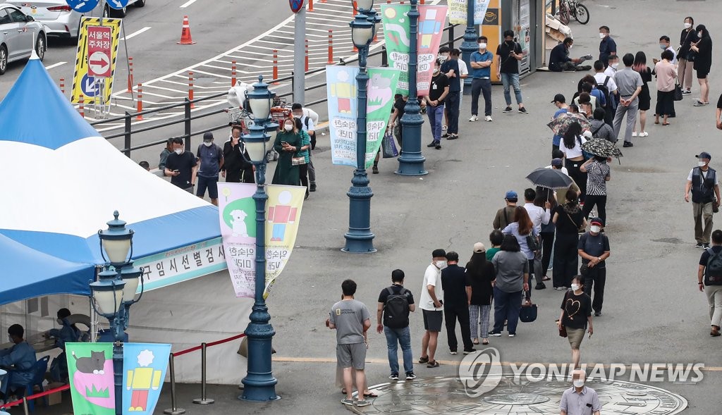 People stand in line to take coronavirus tests at a screening clinic in front of Seoul Station on July 13, 2021. (Yonhap)
