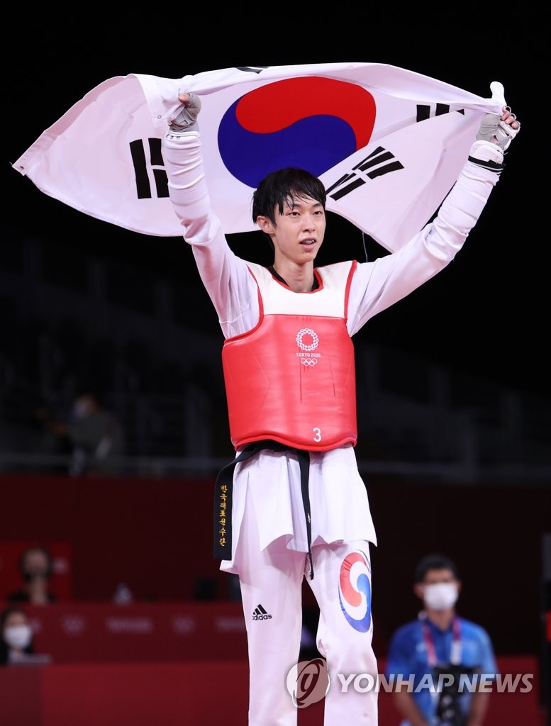 Jang Jun of South Korea holds up the national flag, Taegeukgi, to celebrate his bronze medal in the men's 58kg taekwondo event at the Tokyo Olympics at Makuhari Messe Hall A in Chiba, Japan, on July 24, 2021. (Yonhap)