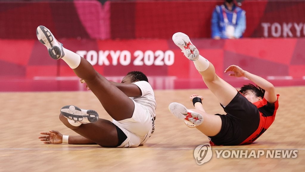 Wuta Dombaxi of Angola (L) Kang Kyung-min of South Korea fall to the floor during the teams' Group A match of the Tokyo Olympic women's handball tournament at Yoyogi National Stadium in Tokyo on Aug. 2, 2021. (Yonhap)