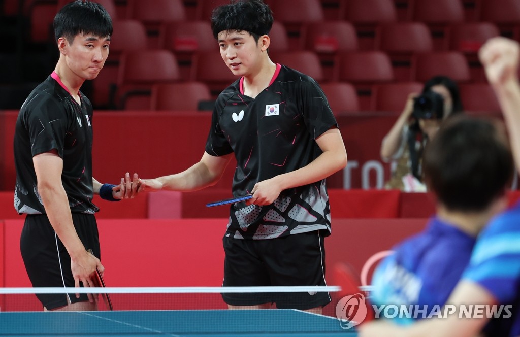 Lee Sang-su (L) and Jeoung Young-sik of South Korea react to their doubles loss to Jun Mizutani and Koki Niwa of Japan in the bronze medal match for the men's table tennis team event at the Tokyo Olympics at Tokyo Metropolitan Gymnasium in Tokyo on Aug. 6, 2021. (Yonhap)