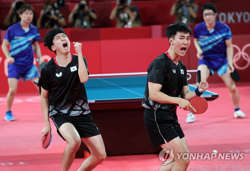 Jeoung Young-sik (L) and Lee Sang-su of South Korea celebrate a point against Koki Niwa and Jun Mizutani of Japan during their doubles match of the bronze medal contest for the men's table tennis team event at the Tokyo Olympics at Tokyo Metropolitan Gymnasium in Tokyo on Aug. 6, 2021. (Yonhap)