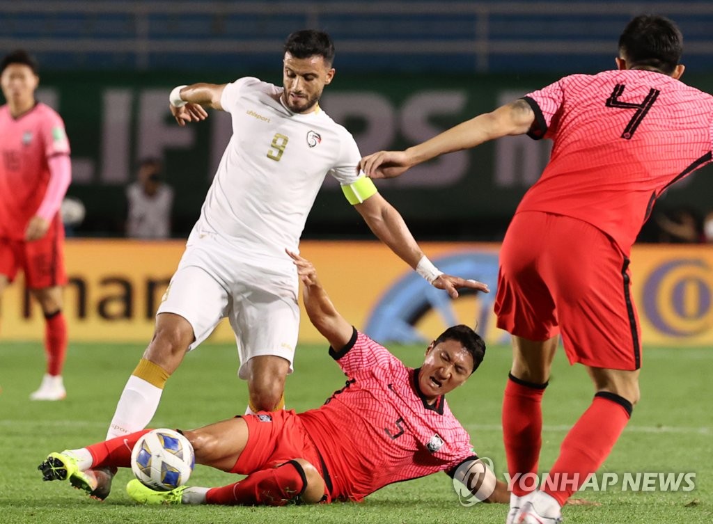 Jung Woo-young of South Korea (C) tackles Omar Al Somah of Syria during the teams' Group A match in the final Asian qualifying round for the 2022 FIFA World Cup at Ansan Wa Stadium in Ansan, Gyeonggi Province, on Oct. 7, 2021. (Yonhap)