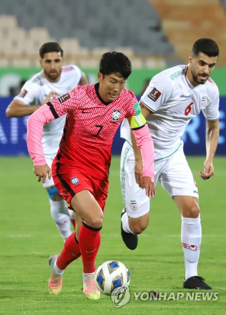 Son Heung-min of South Korea (L) tries to dribble past Saeid Ezatolahi of Iran (R) during the teams' Group A match in the final Asian qualifying round for the 2022 FIFA World Cup at Azadi Stadium in Tehran on Oct. 12, 2021. (Yonhap)