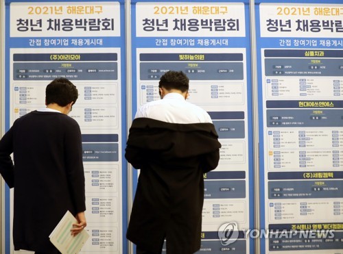 La foto, tomada el 1 de noviembre de 2021, muestra a unos demandantes de empleo mirando un tablón de anuncios en una feria de empleo, en Busan.
