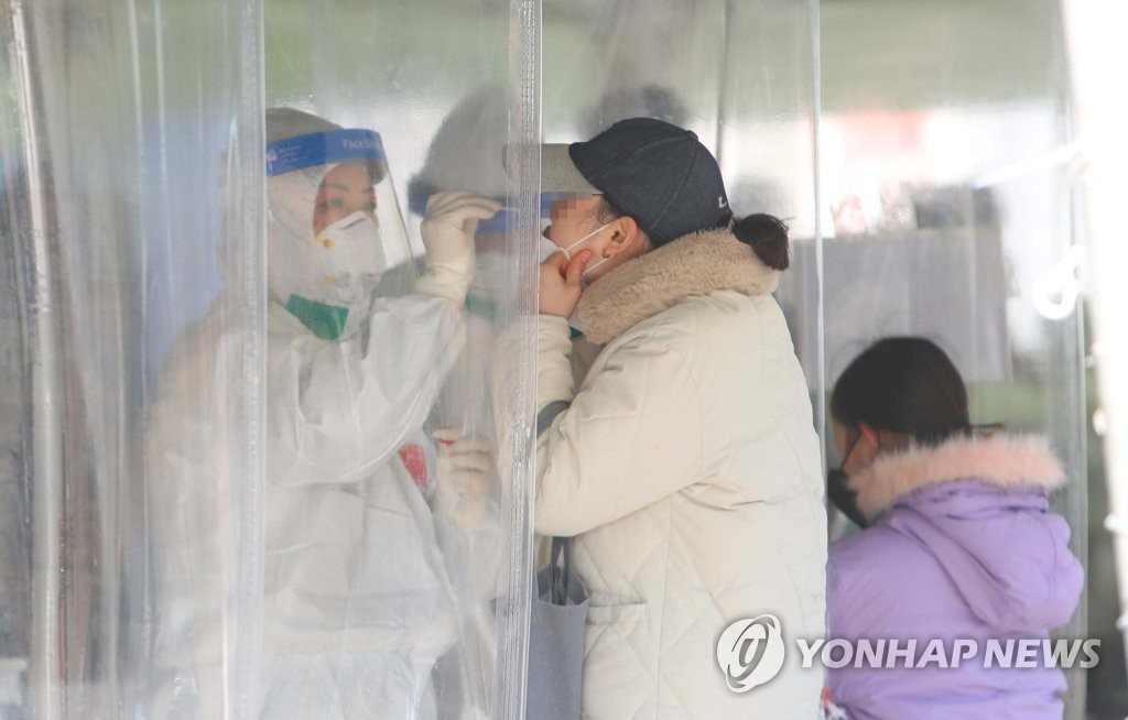 This photo taken Jan. 21, 2022, shows a woman taking a coronavirus test at a makeshift testing center in Daegu, 300 kilometers south of Seoul. (Yonhap)