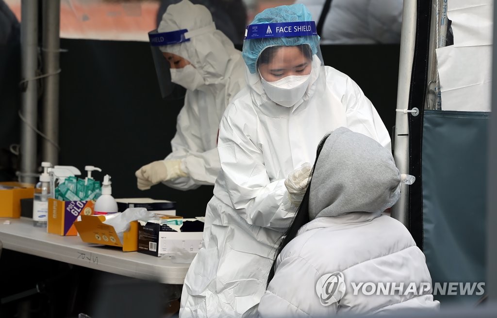 Medical workers carry out rapid antigen tests at a COVID-19 testing station in Seoul on Feb. 13, 2022, as South Korea hit a daily high of 56,431 new COVID-19 infections. (Yonhap)