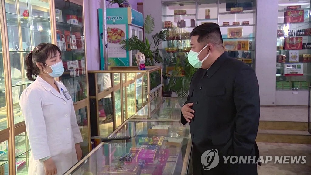 In this image from a broadcast by the North's Korean Central Television on May 16, 2022, leader Kim Jong-un (R) inspects a pharmacy in Pyongyang the previous day wearing two masks. (For Use Only in the Republic of Korea. No Redistribution) (Yonhap)