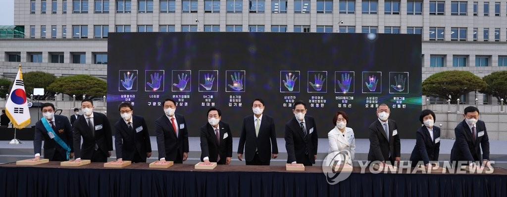 President Yoon Suk-yeol (C) and chiefs of South Korea's largest conglomerates participate in a handprint ceremony during a conference of small and medium-sized enterprises at the presidential office complex in Yongsan, central Seoul, on May 25, 2022. (Yonhap)
