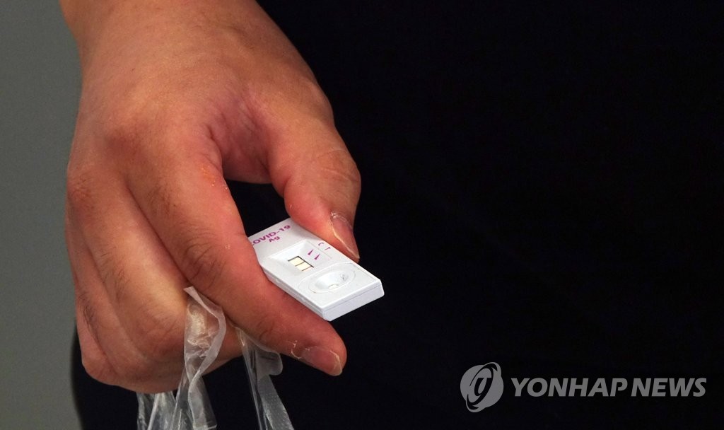 A person holds a COVID-19 kit displaying a positive result at a testing station at Seoul Station in Seoul on June 13, 2022. (Yonhap)