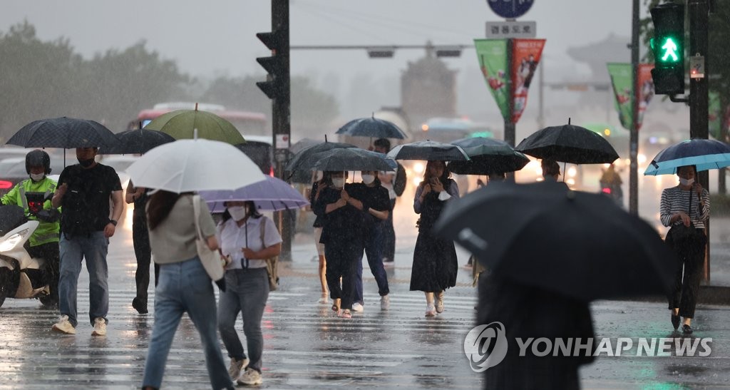 People holding umbrellas cross a street at the Gwanghwamun intersection in the rain in Seoul on June 23, 2022. The annual rainy season began on the day, with most of the country forecast to receive heavy rainfall through the following day. (Yonhap)