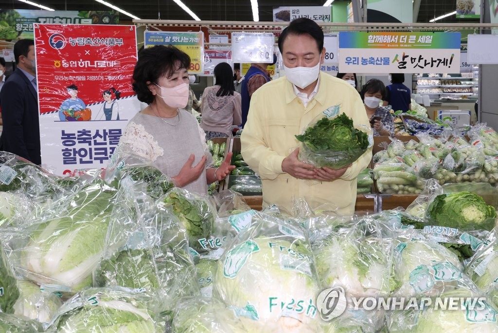 Le président Yoon Suk-yeol (à droite) examine le prix des légumes dans un hypermarché, dans le sud de Séoul, le jeudi 11 août 2022.