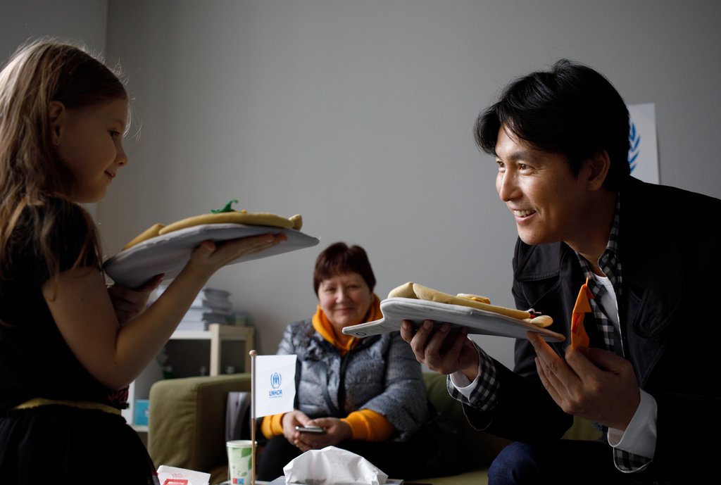 South Korean actor Jung Woo-sung (R), a goodwill ambassador for United Nations High Commissioner for Refugees (UNHCR) Korea, talks with a refugee girl from Ukraine at a refugee support center in Poland during his one-week "mission" trip early this month, in this undated photo provided by the UNHCR on Oct. 19, 2022. (PHOTO NOT FOR SALE) (Yonhap)
