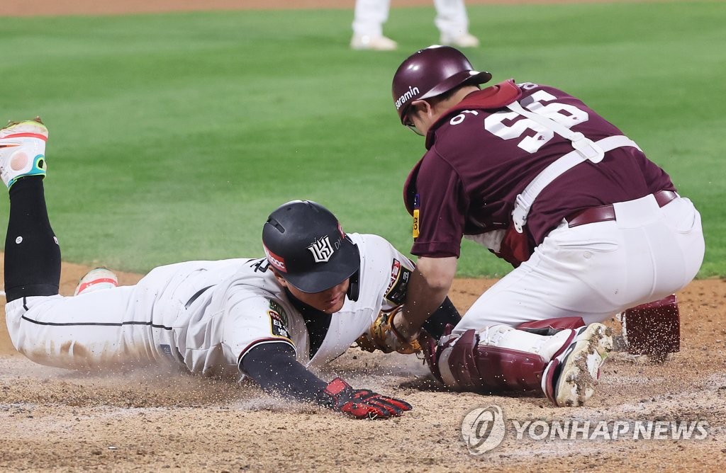 Hwang Jae-gyun of the KT Wiz (L) slides home safely under the tag of Kiwoom Heroes catcher Lee Ji-young during the bottom of the seventh inning of Game 4 of the first round in the Korea Baseball Organization postseason at KT Wiz Park in Suwon, 35 kilometers south of Seoul, on Oct. 20, 2022. (Yonhap)
