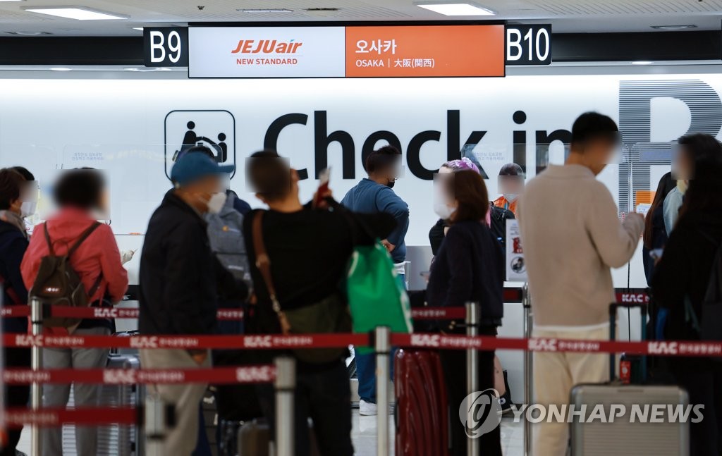 La foto, tomada el 30 de octubre de 2022, muestra a personas esperando en fila para partir a Osaka, Japón, en el Aeropuerto Internacional de Gimpo, en el oeste de Seúl, en medio del alivio de las restricciones antivirus.