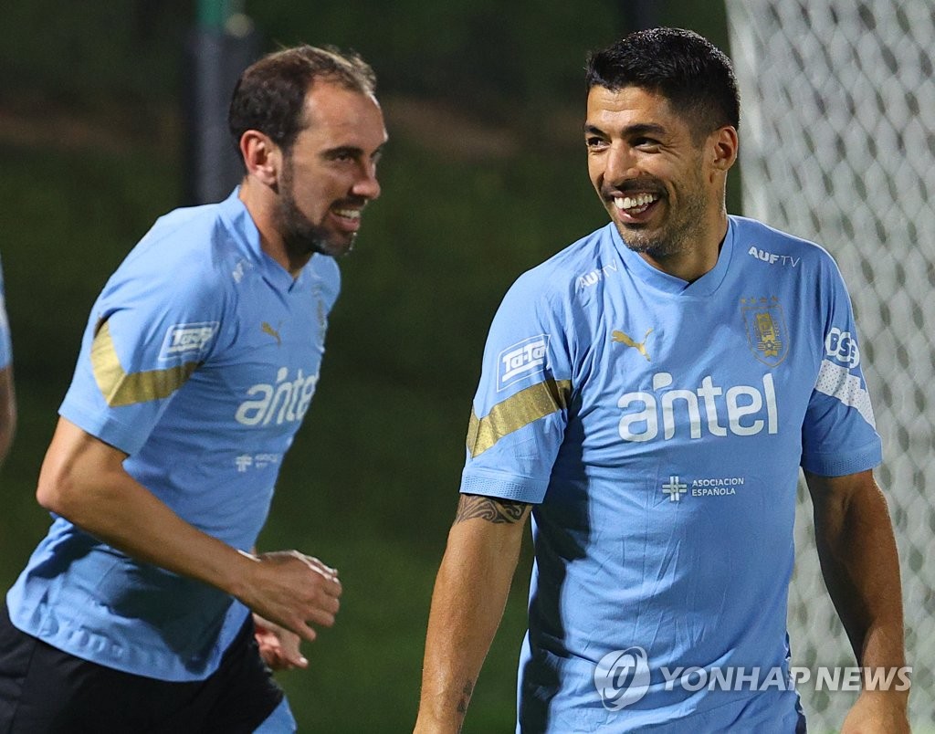 Diego Godin (L) and Luis Suarez of Uruguay chat during a training session for the FIFA World Cup at Al Erssal Training Site in Doha on Nov. 19, 2022. (Yonhap)